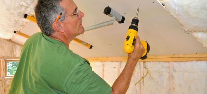 man drilling a hole into the ceiling
