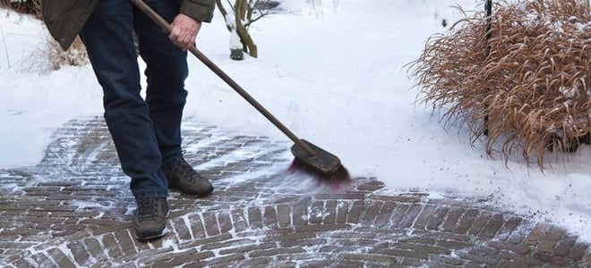 An old man sweeping snow off a walkway. 