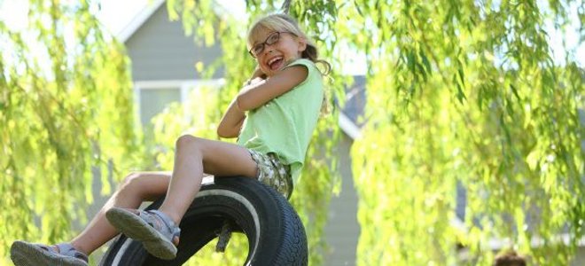 A girl having fun on a tire swing.