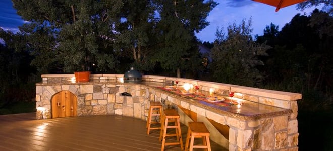 An outdoor deck with an outdoor kitchen and bar. 