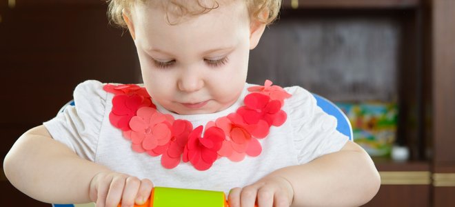 A little girl rolls playdough.