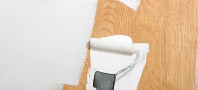 Using a paint roller to paint over wood paneling.