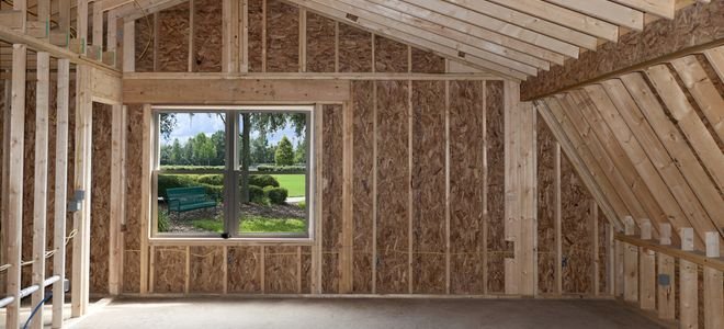 home addition walls and frames under construction, with window out to green area and bench