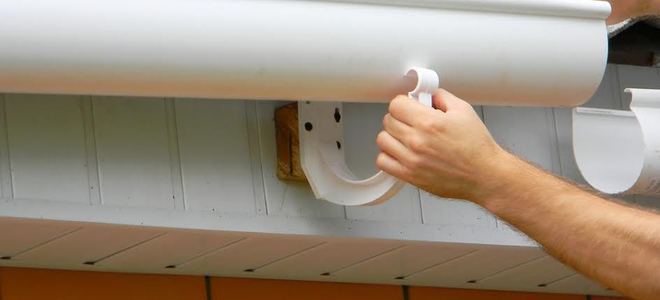 Someone hanging gutters on a roofline.