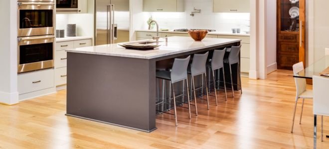 large kitchen island with sink and chairs over wooden floors