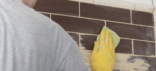 Wiping off excess grout from a backsplash. 