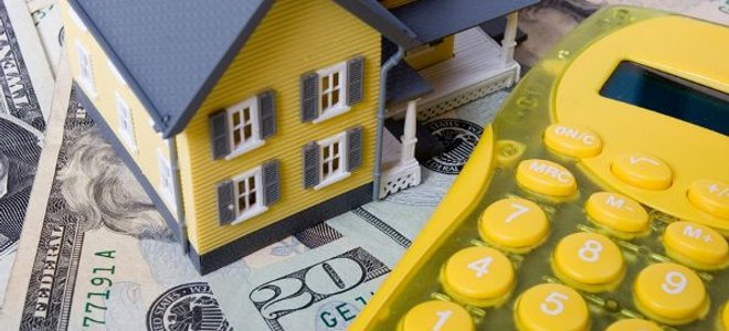 A yellow calculator with cash and a small plastic house.
