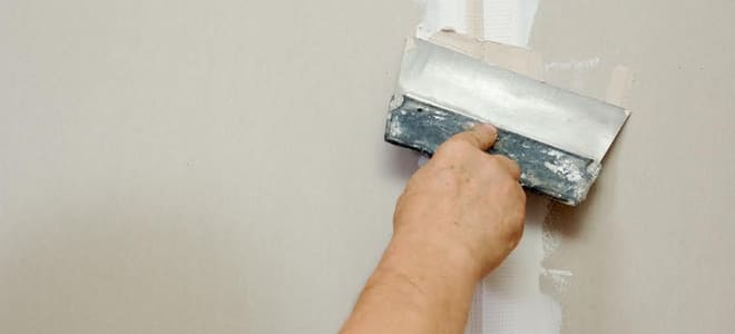 A putty knife taping the seams on drywall. 