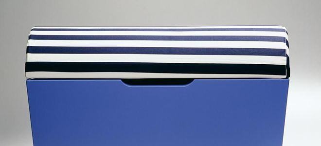 A blue wood ottoman with a striped lid.