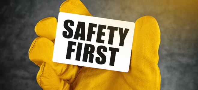 yellow glove holding safety first sign