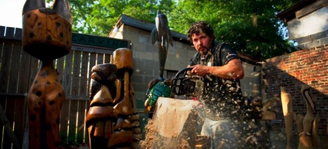 Wood cutting artist using a chainsaw to cut a sculture
