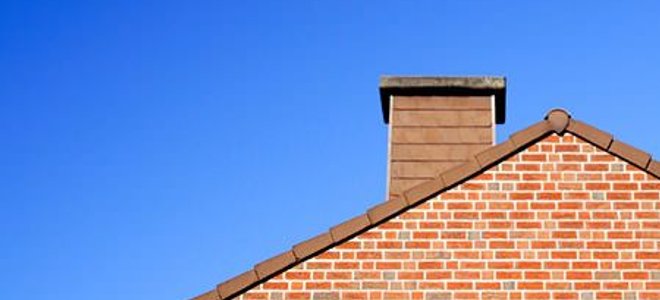 A home roof with a brick chimney extending above it.