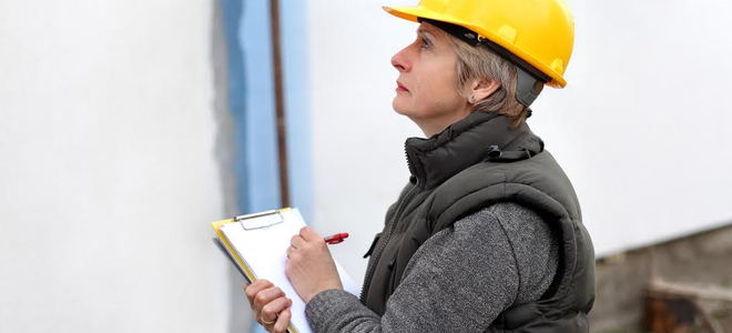 A female building inspector with a hard hat and a clipboard. 