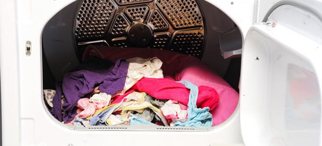 A dryer with a pile of colorful laundry in it. 
