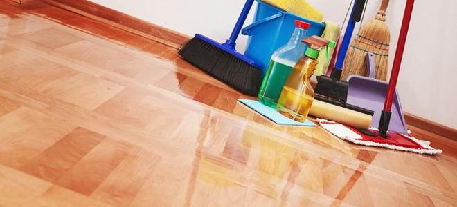A pile of cleaning supplies on a shiny wood floor.