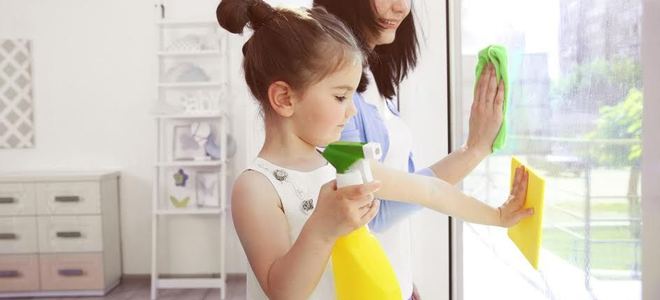A mom and young girl cleaning windows in a house.