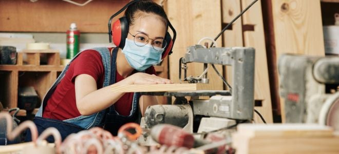 girl in mask using power saw