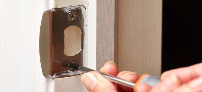 hands screwing in door latch plate