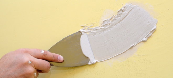 hand filling hole with spackle