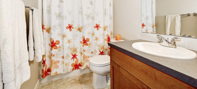 shower curtain with red and orange flower design in bathroom with tile floor
