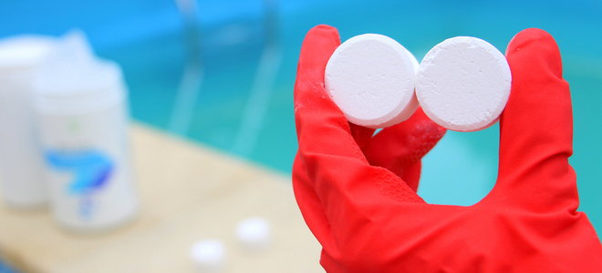 gloved hand holding pool cleaning tablets