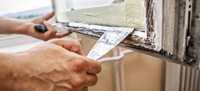 руки с помощью шпателя глазурируют конопатку на старом окне