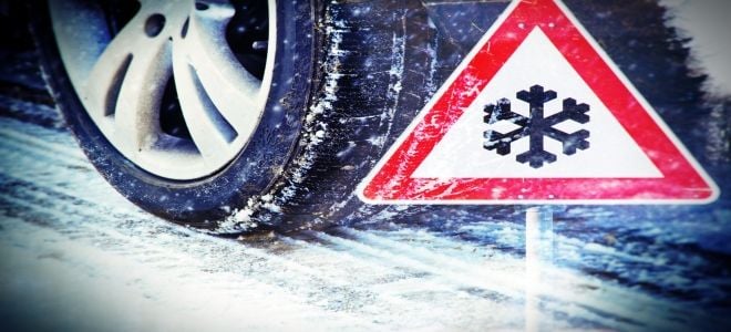 A car tire in front of a snowflake sign. 