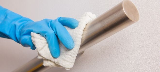 gloved hand cleaning railing with a cloth