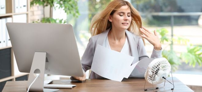 woman fanning herself in home office