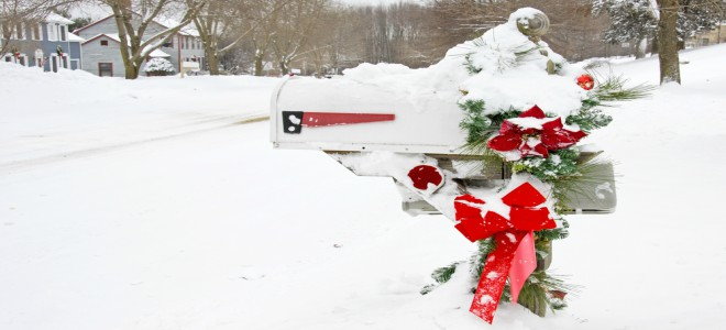 A mailbox in the snow decorated for Christmas with bows and garland. 