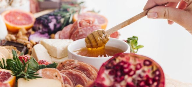 honey on charcuterie board with fruit and cheese