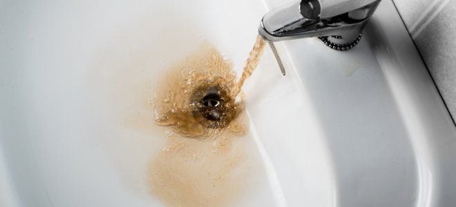 Brown water coming out of a faucet in a white sink