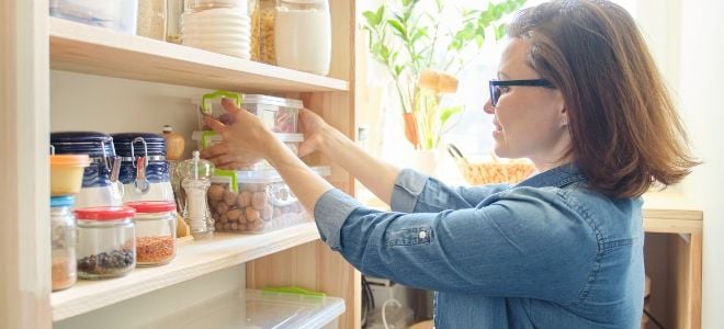 woman adjusting foodstuffs on a pantry shelf