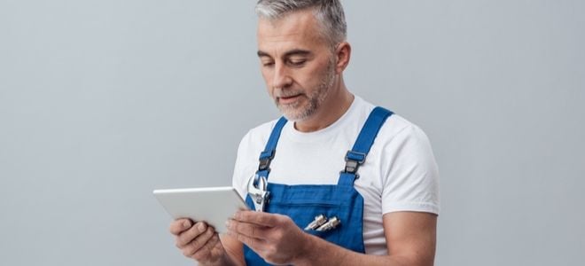 a man doing plumbing checks a tablet computer