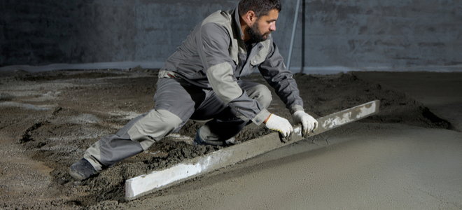 person flattening concrete with a long, even board