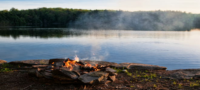 A camp fire by a lake.