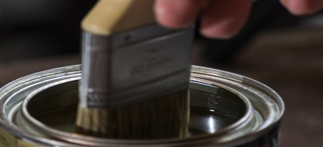 dipping paintbrush into can of stain