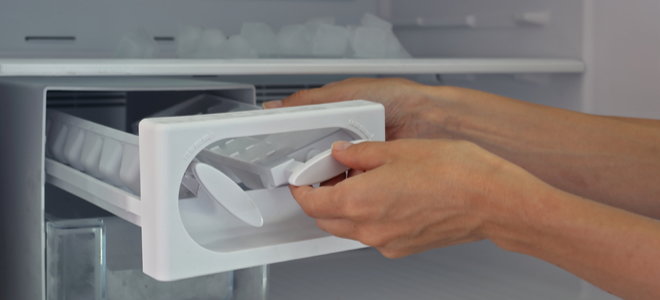 hands emptying ice trays from freezer
