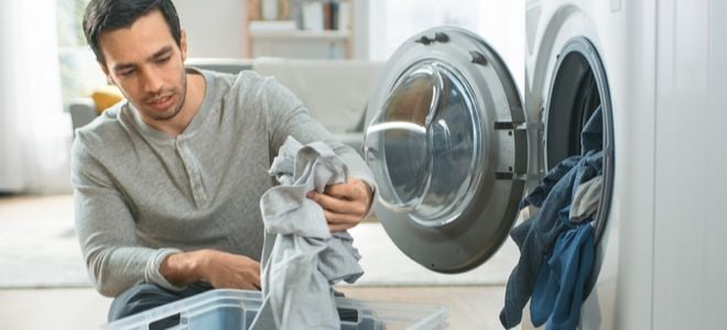 man doing laundry looking at gray shirt