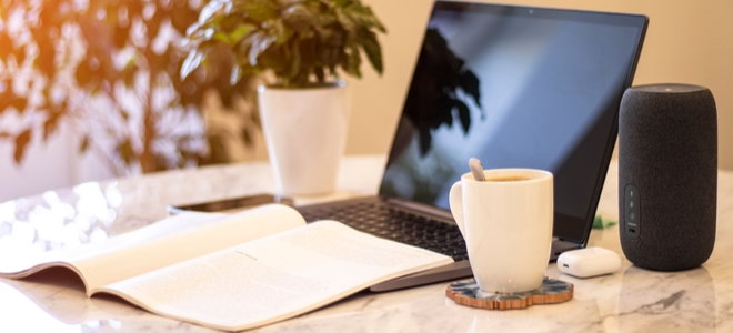 laptop with journal smart speaker and coffee in home work area