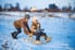 Two kids playing on a sled in the snow.