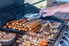 an open grill with a stack of hot dogs and other meats cooking.