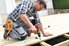 man building a wood deck with a drill gun