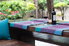 backyard patio with dark wooden table, wine glasses and bottle, and blue and purple fabrics