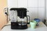 a coffeemaker on the counter with cups nearby