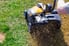 person pushing lawn aeration device over grass