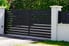 dark colored aluminum driveway gate between white pillars