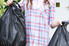 woman carrying two bags of garbage