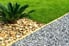 A xeriscaped yard with gravel, grass, and a palm tree.