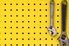 yellow painted pegboard with hanging wrenches